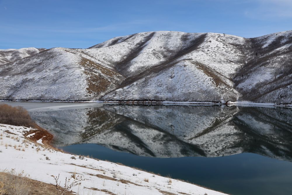 A view of the Little Del Reservoir, showing a lake surrounding by large hills